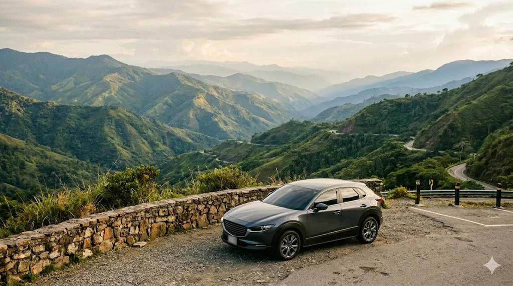 A car parked at an overlook above an Antioquian mountain road, green ridges rolling into the distance